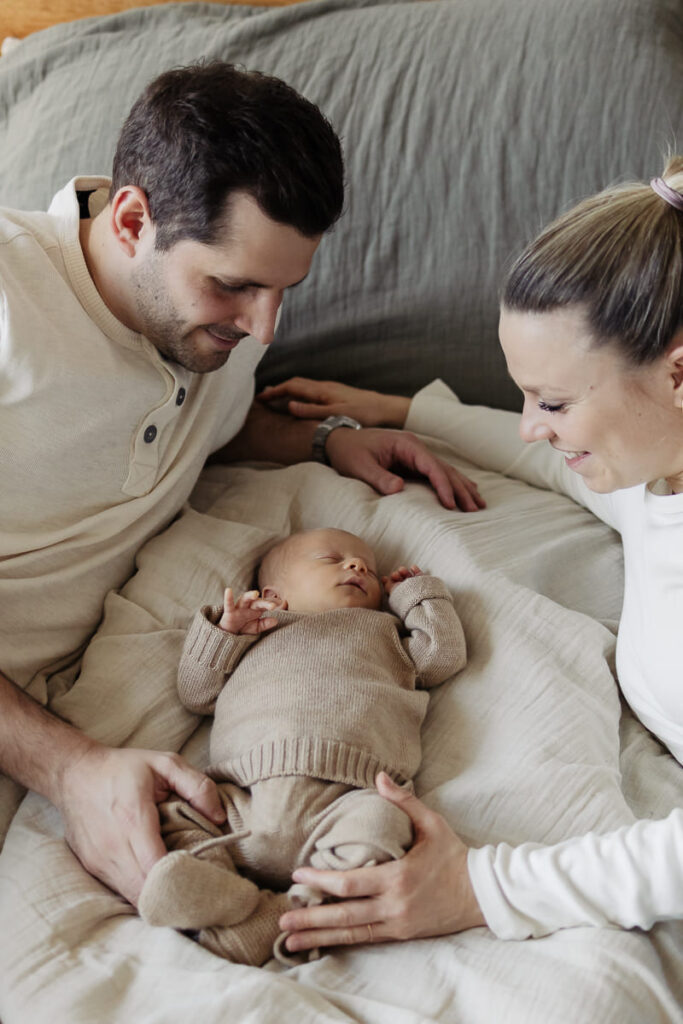 Newborn Fotoshooting Zürich, Eltern schauen ihr Baby lächelnd an