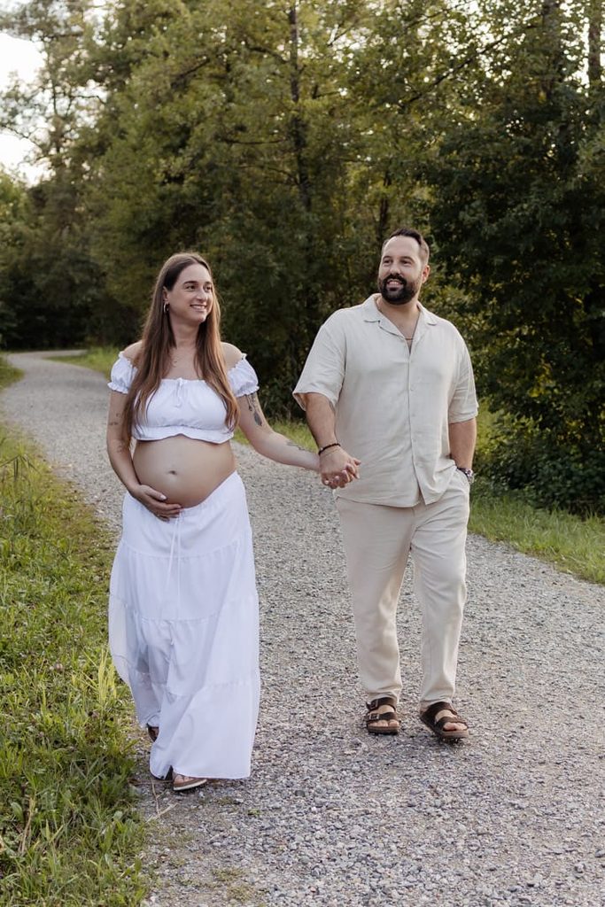 Paar geht Hand in Hand beim Babybauchshooting