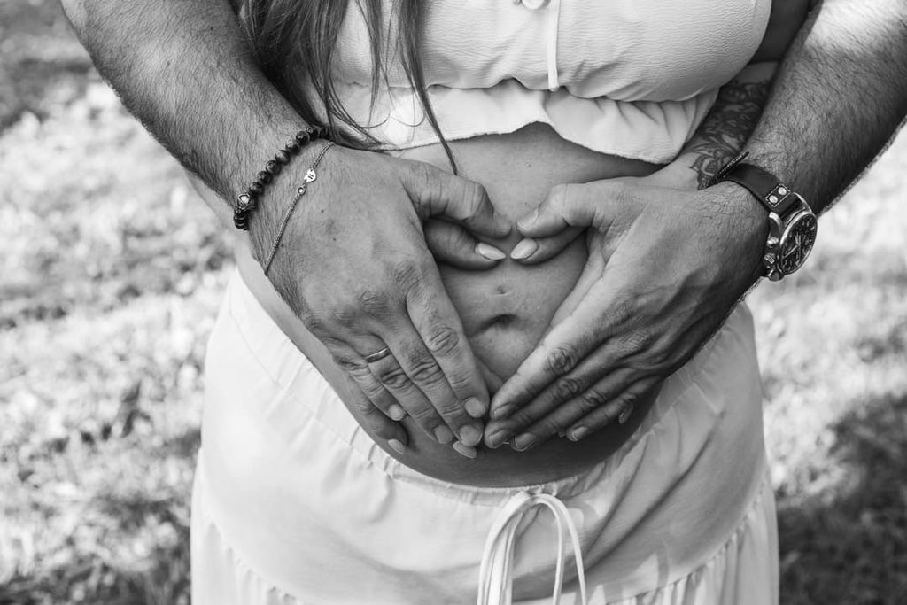 Schwangerschaftsshooting im Freien: Hände auf dem Babybauch