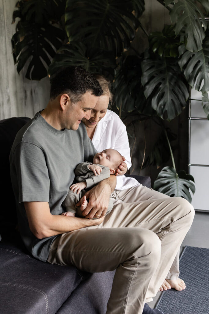 Eltern kuscheln zuhause mit ihrem Baby beim Fotoshooting