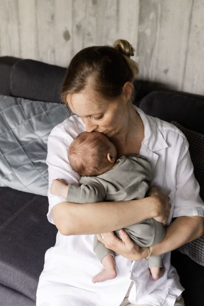 Mama hält ihr Baby beim Babyshooting zuhause im Arm