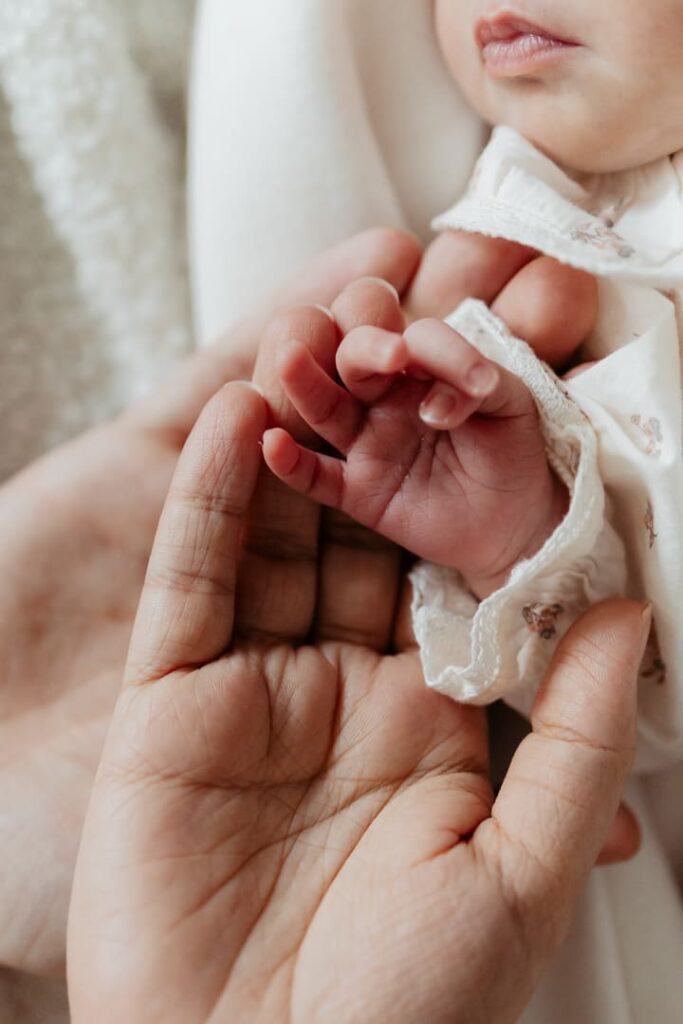 Babyhand auf den Händen von Mama und Papa